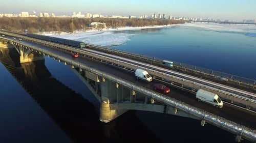 U-Bahn fährt auf der Brückenbahn über den Fluss in Winter City. Luftaufnahme Autofahren auf der Autobahn...
