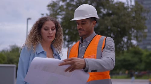 Architects Reviewing Blueprints on Construction Site Together