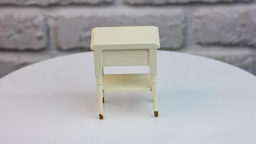 Toy wooden piece of furniture in studio. Tiny white nightstand with a cute drawer