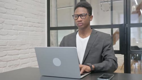 Young Professional Typing on Laptop in Modern Office