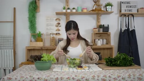 Young Woman Tossing Fresh Salad in Bright Kitchen
