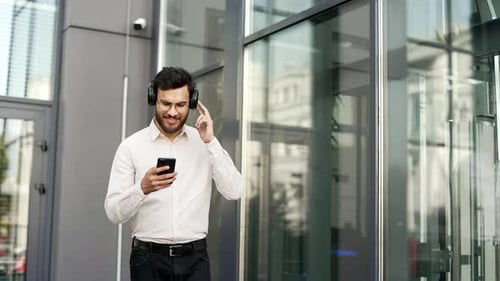 Adult Using Mobile Phone with Headphones in Urban Setting