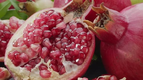 Pomegranate fruits with slices and pomegranate tree leaves slowly move in the frame