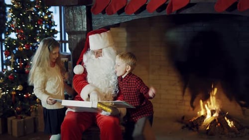 Niños alegres con Papá Noel cerca del árbol de Navidad