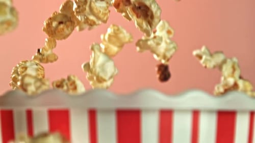 Popcorn falling into container with red and white stripes