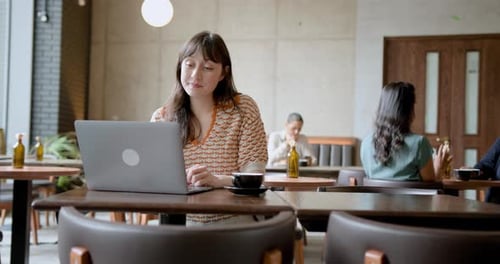 Young Female Freelancer using Laptop, Working from a Cafe