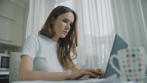 Woman Working at Home on Laptop, Feeling Stressed
