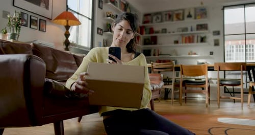Woman Using Phone, Sitting on Floor With Package