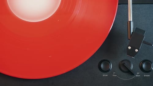 Red Vinyl Record Spinning on Black Turntable