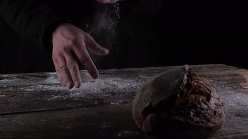 Hands Sprinkle Flour on Freshly Baked Bread