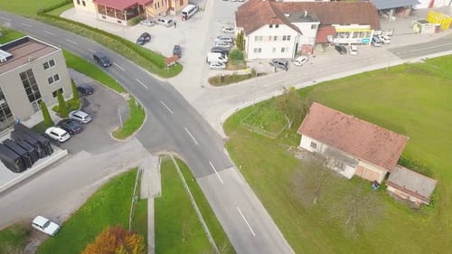 A black car heading speedily on the road, crossing a road square in the town.
