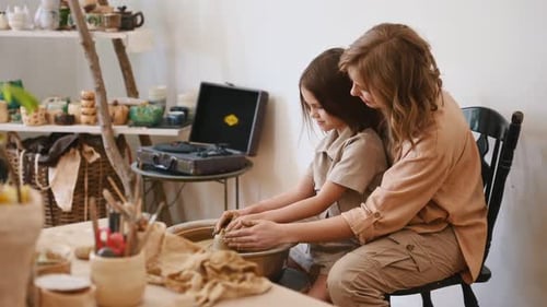 Woman and Child Creating Pottery Together at Wheel