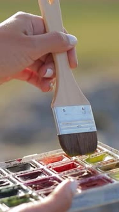 Woman Painting Watercolor with Brush Outdoors