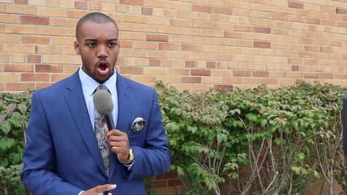 Young Man Interviewed with Microphone Outside
