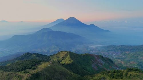 Aerial view of green lush mountain range with layers of misty hills and dramatic peaks