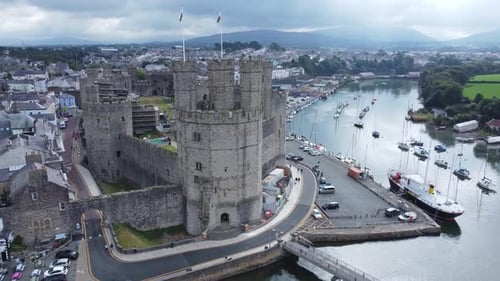 Ancient Caernarfon castle Welsh harbour town aerial view medieval waterfront landmark misty mountain