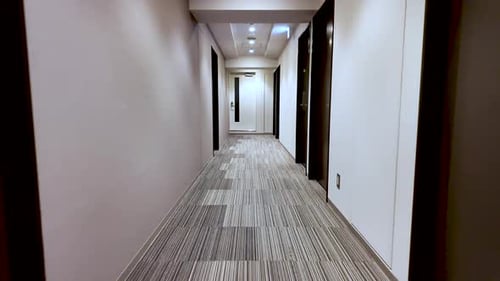 Walking down an empty hotel corridor with doors on each side. slow motion