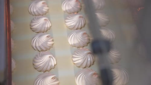 Delicious creamy marshmallow sweets moving slowly on the conveyor belt.