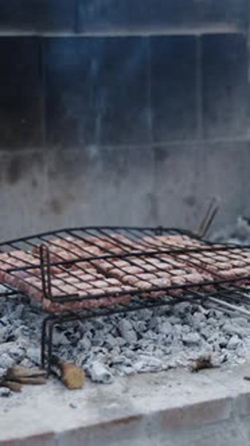 Blick auf einen Grill in der Glut und das Feuer daneben