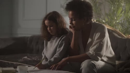 Woman Helping Young Girl with Homework Indoors