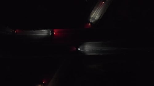 Aerial drone view of a highway interchange at night with cars moving along elevated roads.