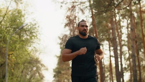 Young Muscular Athlete Running at a Leisurely Pace with a Tense Face in a City Park Concept of