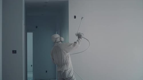 Painter Sprays White Paint on Wall