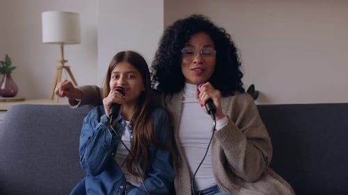 Woman and Girl Singing Karaoke on Sofa