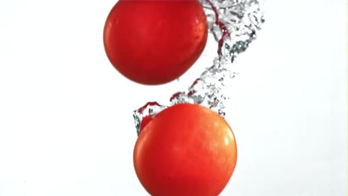 Tomatoes Falling Under Water on a White Background Filmed on a Highspeed Camera at 1000 Fps