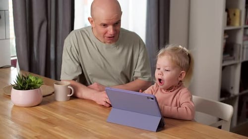 A Child with Cochlear Implants Plays with a Tablet Computer with His Father