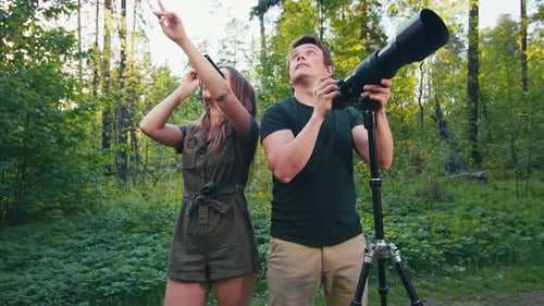 Observation des
oiseaux dans le parc. Couple observant les oiseaux avec des jumelles et un appareil photo avec téléobjectif