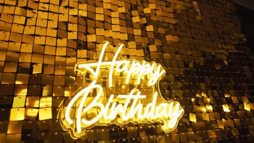 A Vibrant and Festive Golden Happy Birthday Neon Sign Set Against a Sparkling and Colorful