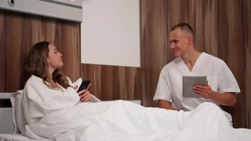 in Modern Clinic in a Bright VIP Room a Young Girl in a White Coat Lies on the Bed Consulting a