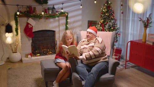 Girl and Adult Reading a Book at Christmas