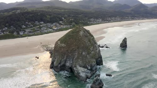 Close up 4k aerial of haystack rock in canon beach oregon. West coast drone shot with waves and tree