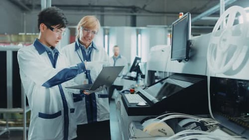 On High Tech Factory Worker Load Reels into Pick and Place Machine, Engineers Use Computer for Prog