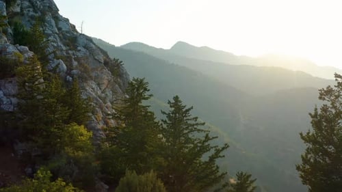 Marvelous mountain range view at sunset with cliff in foreground. Camera is moving up.