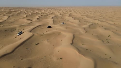 Vista aérea de vehículos SUV que atraviesan vastas dunas del desierto