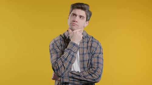 Young Adult Man Thinking on Yellow Background