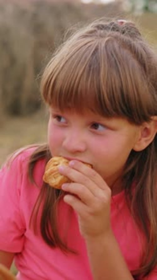 Little Kid Enjoying Snacks with Boy in Open Field Eating Pastries