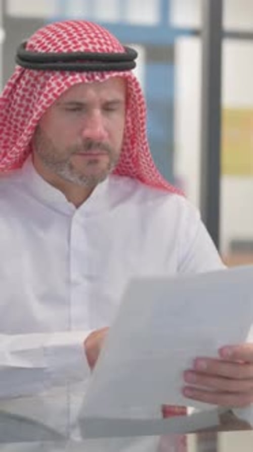 Thoughtful Man Reviewing Documents Wearing Traditional Keffiyeh