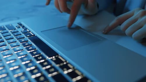 Hands Using Laptop Trackpad with Illuminated Keyboard