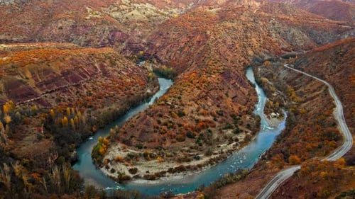Aerial View of Winding River Through Mountains in Autumn