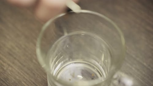 Instant Coffee Granules are Poured Into a Glass Cup Top View Slow Motion