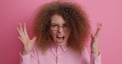 Frustrated Woman Shouts and Clenches Fists on Pink Background