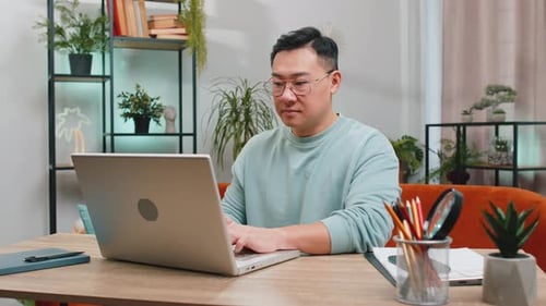 Man Working on Laptop at Home Desk