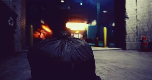 Discarded Bag Sits on Alley Floor Near Urban Entrance at Night