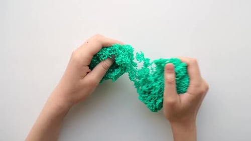 Hands Playing with Textured Slime with Bubbles Stretching the Gooey Substance on White Background