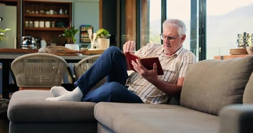Senior Man Relaxing and Reading on Couch Indoors