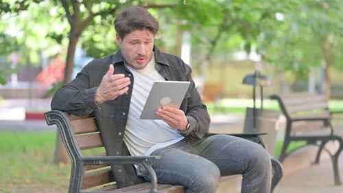 Man on Park Bench Getting Angry With Tablet